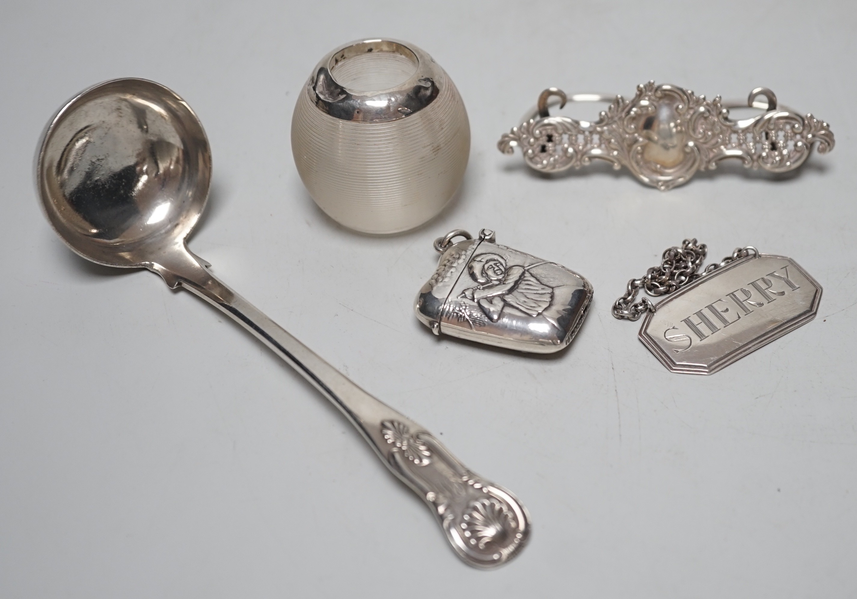A small Edwardian silver mounted ribbed glass match tidy, height 40mm, a Georgian Scottish Kings pattern sauce ladle, a silver menu holder, modern silver wine label and a 925 golf related vesta case.
